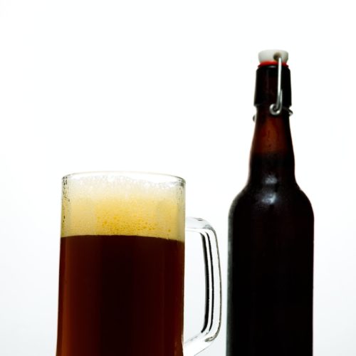 Dark beer in a glass and a bottle of beer on a white background