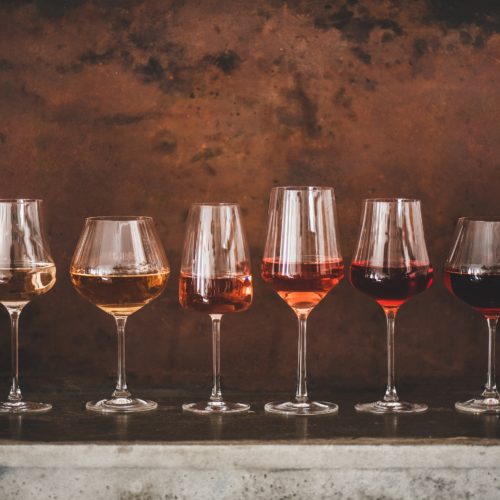 Different shades of Rose wine in glasses over brown background