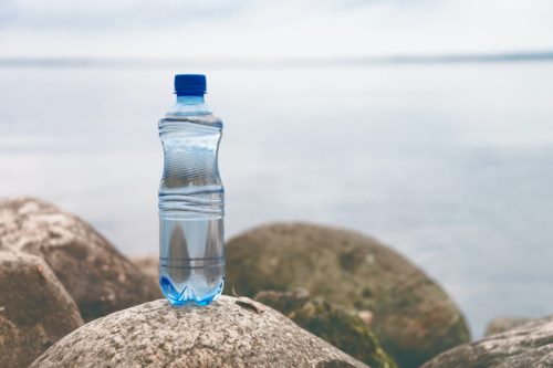 Small water bottle on the ocean stone in natural background