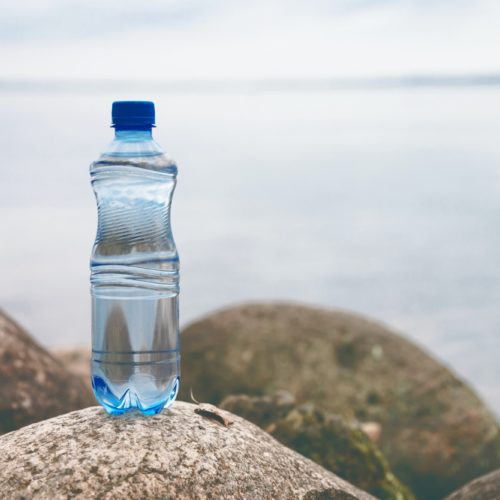 Small water bottle on the ocean stone in natural background